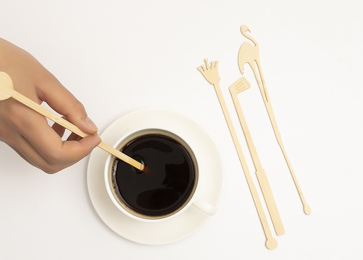 Various different shapes of customized compostable splinter-free wood coffee stir sticks next to the coffee