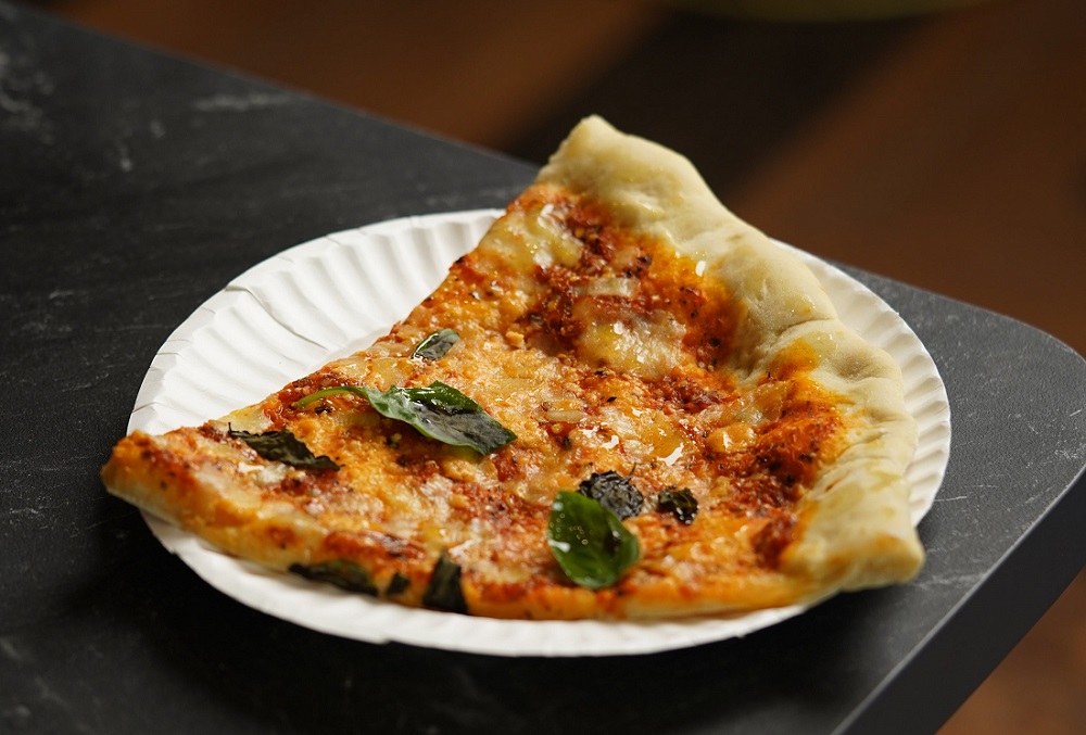 slice-of-pizza-with-fresh-basil-on-a-white-paper-plate