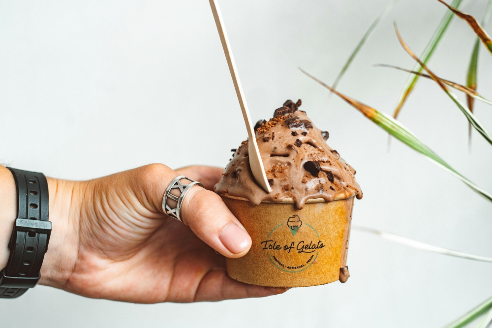 A man eats ice cream with a compostable wooden spoon.