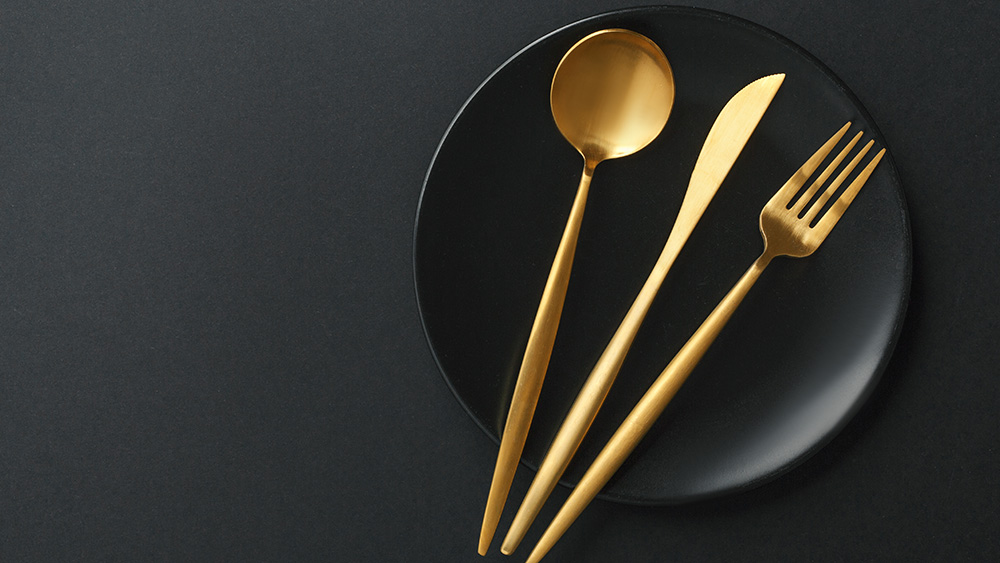 Gold plated utensils on a black ceramic plate