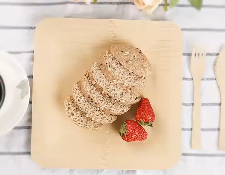 Bread and strawberries on a bamboo plate. Bamboo cutlery on the side.