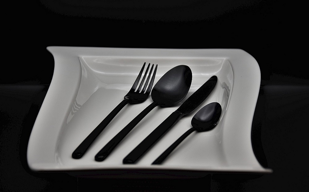 Soup bowls with black disposable plastic cutlery sets in them.