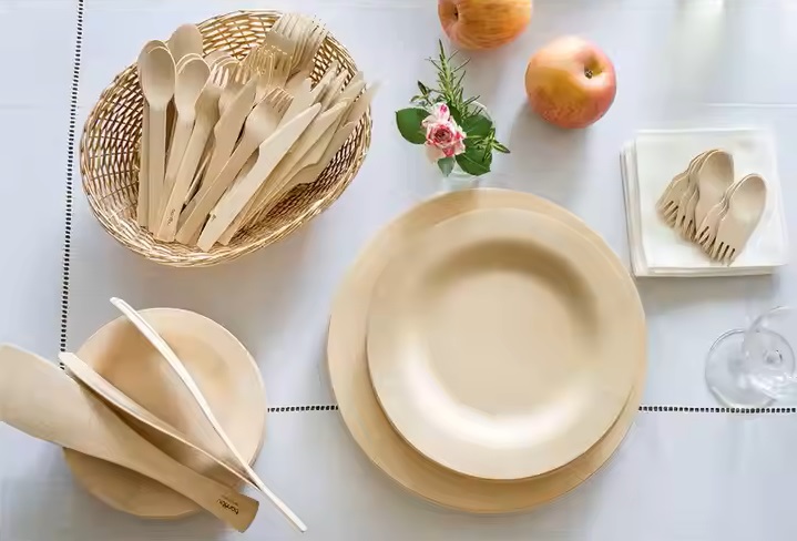 Biodegradable birch dinnerware on the table including disposable plates, disposable cutlery sets and wooden sporks.