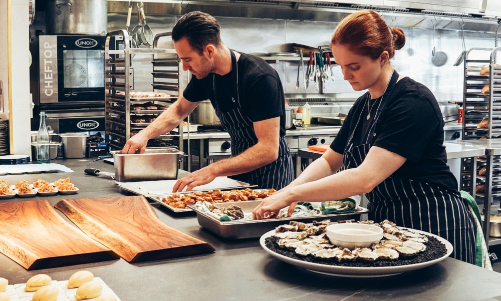 Employees at the sustainable restaurant are setting out plates.
