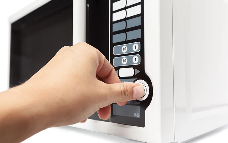Man pressing microwave button