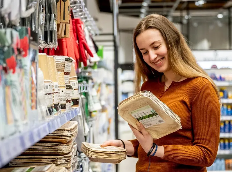 Consumers are selecting plant-based plates in the tableware section of a retail store